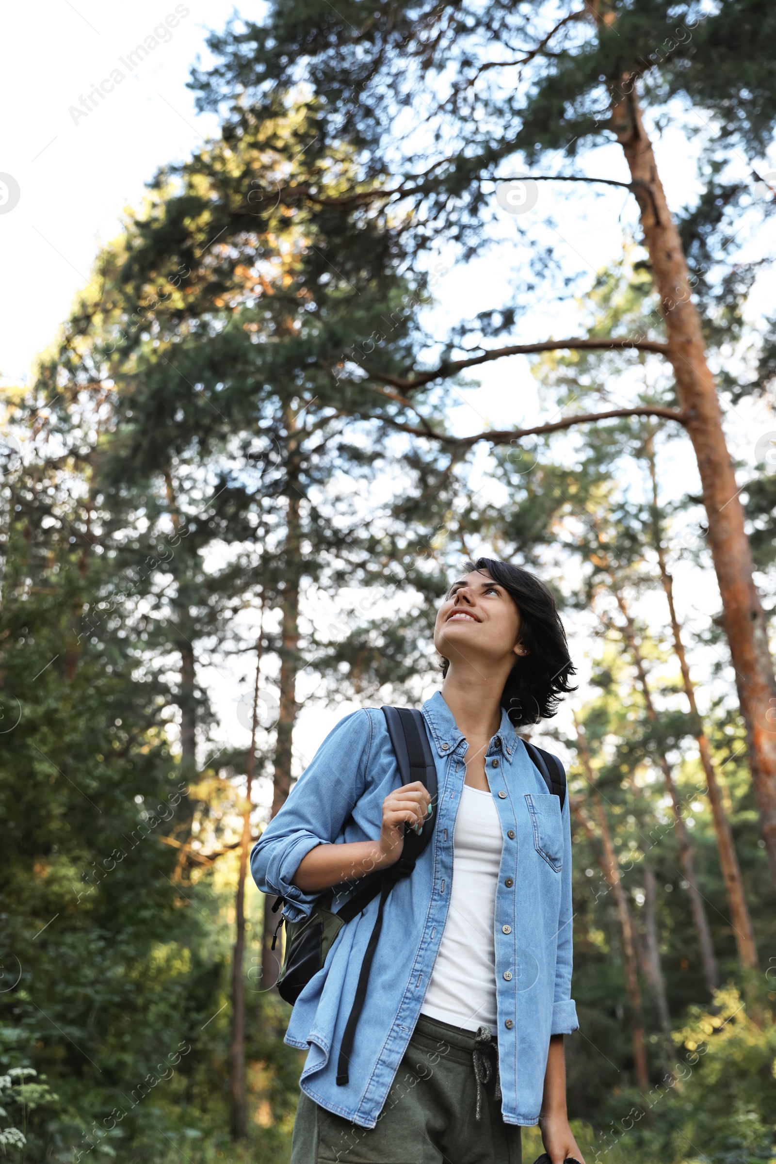 Photo of Young woman with backpack in forest on summer day. Camping season