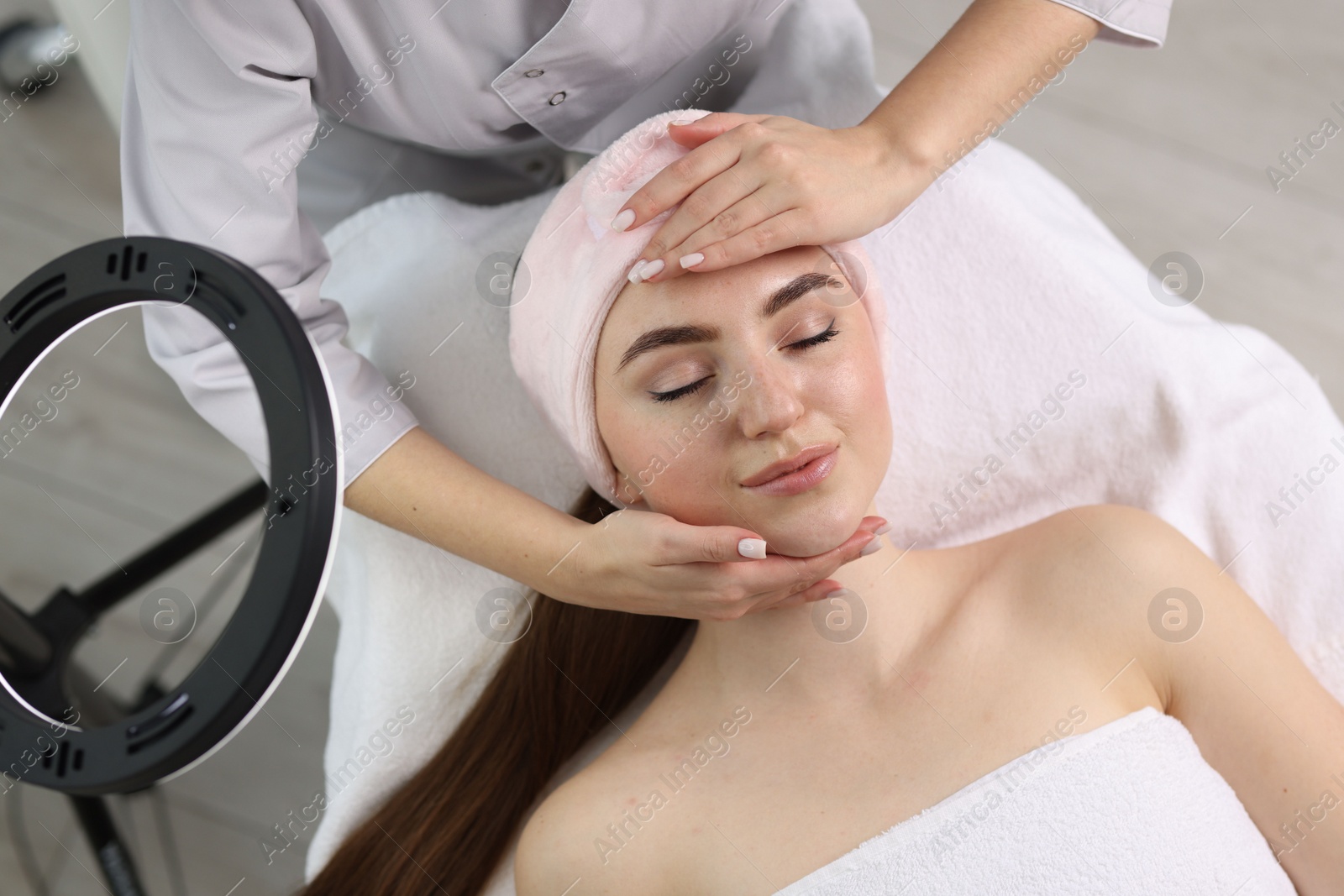 Photo of Cosmetologist making face massage to client in clinic, top view