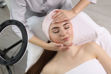 Cosmetologist making face massage to client in clinic, top view