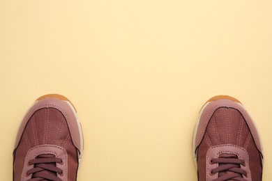 Photo of Pair of stylish kid's sneakers on beige background, top view. Space for text