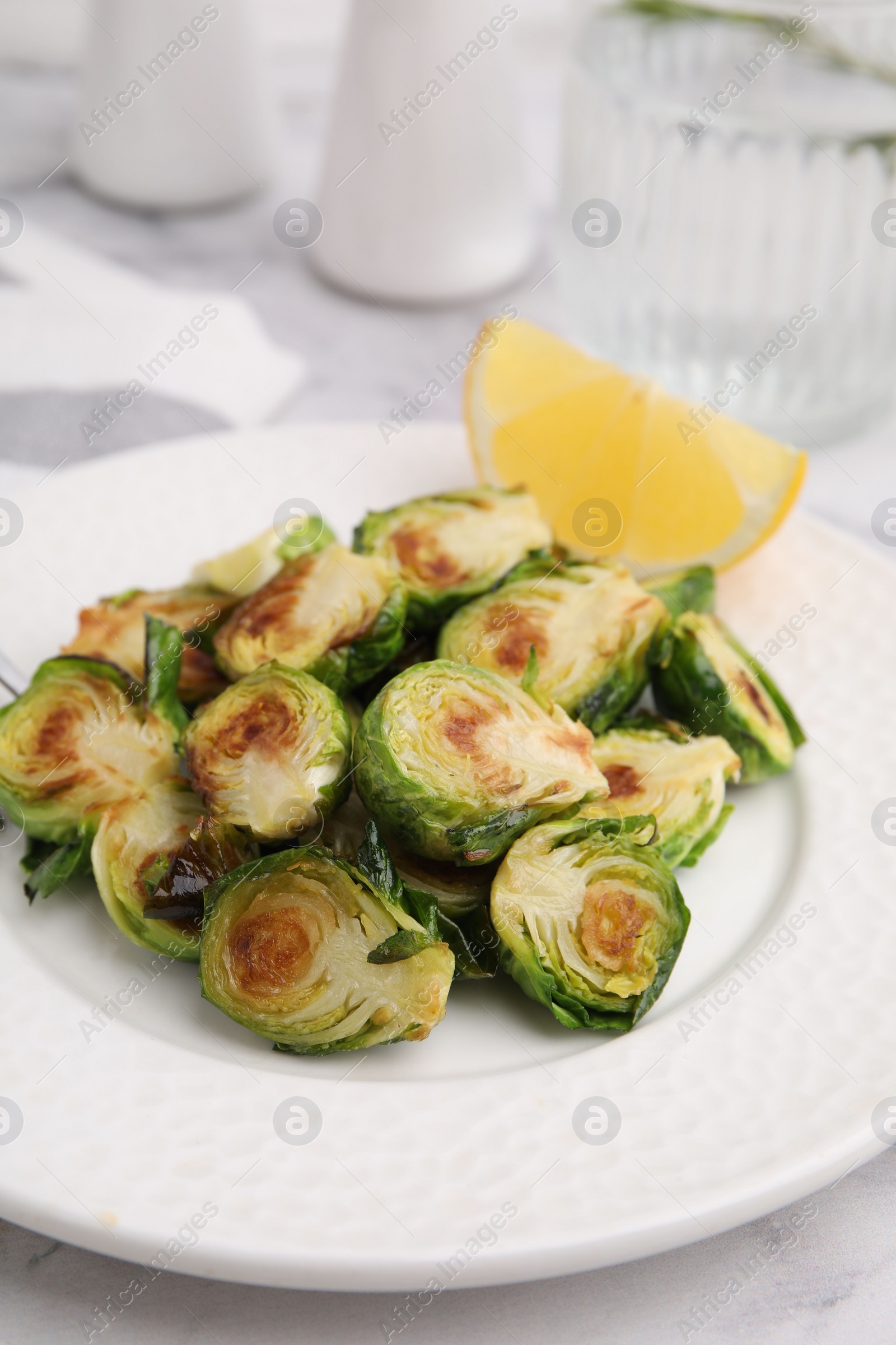 Photo of Delicious roasted Brussels sprouts and slice of lemon on table, closeup