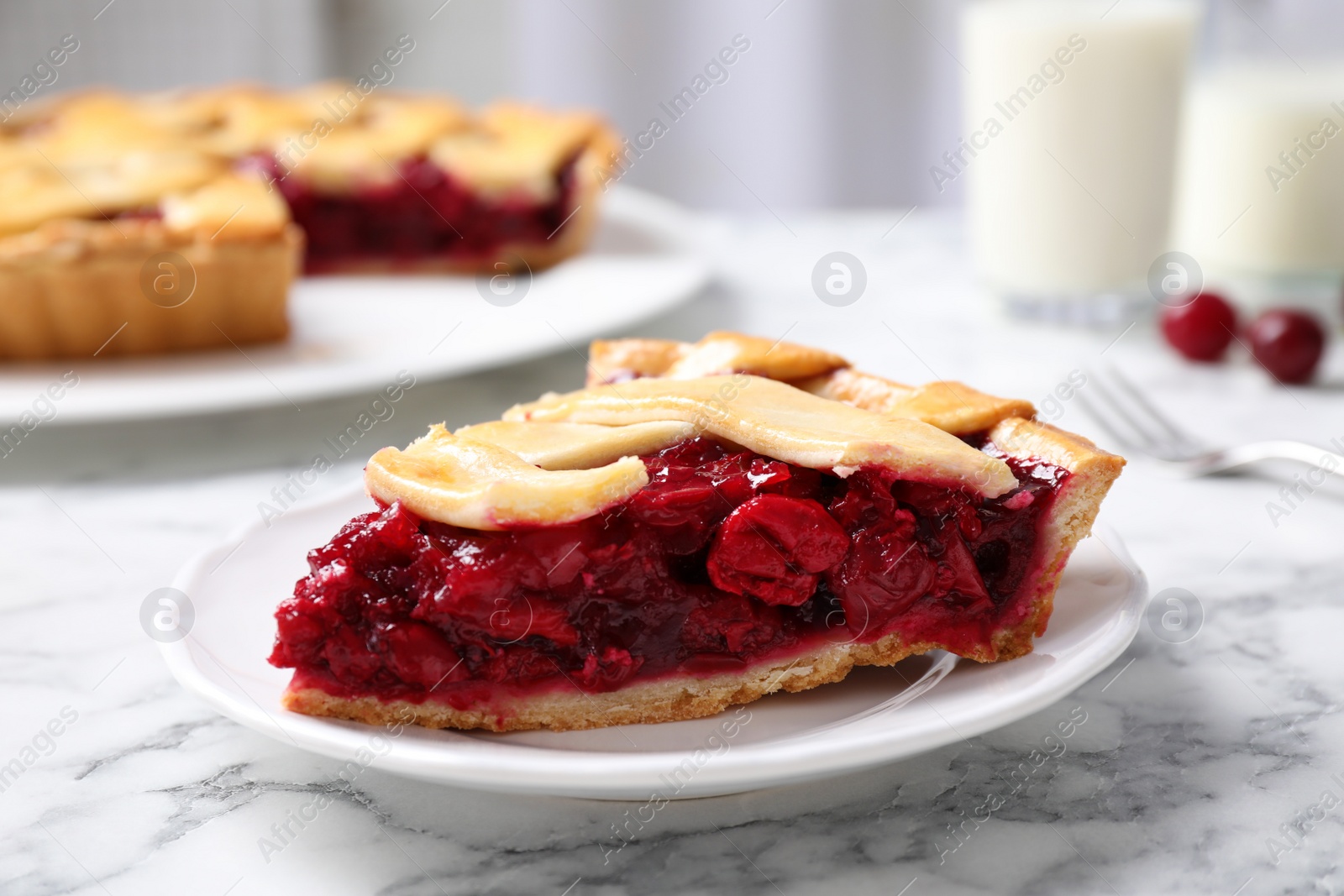 Photo of Slice of delicious fresh cherry pie on white marble table, closeup