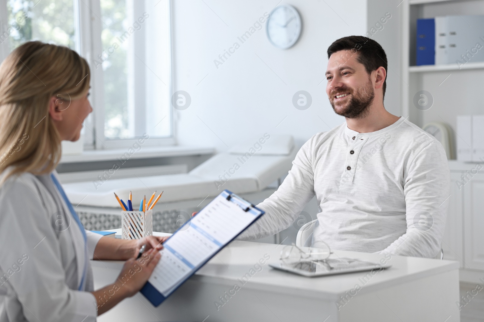 Photo of Professional doctor working with patient at white table in hospital