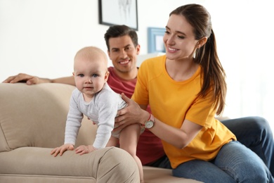 Happy parents with little baby on sofa in living room