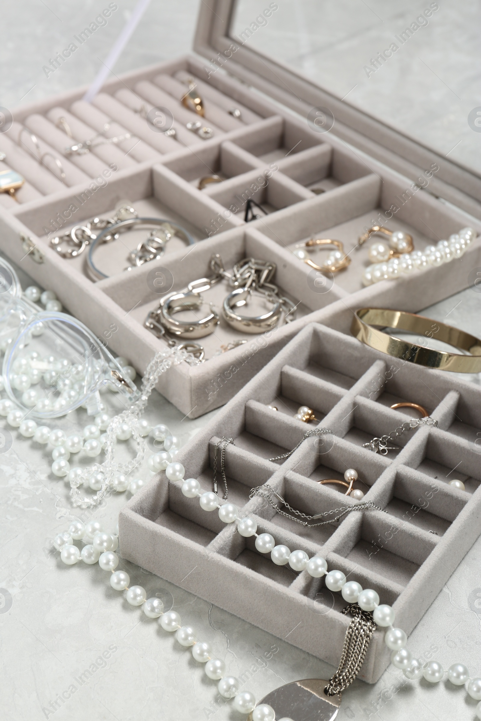 Photo of Jewelry boxes with many different accessories on light grey table, closeup