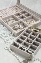 Jewelry boxes with many different accessories on light grey table, closeup