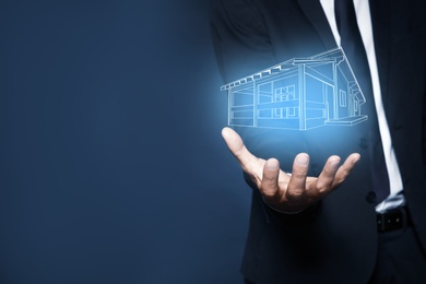 Image of Real estate agent demonstrating house illustration on dark background, closeup. Space for text