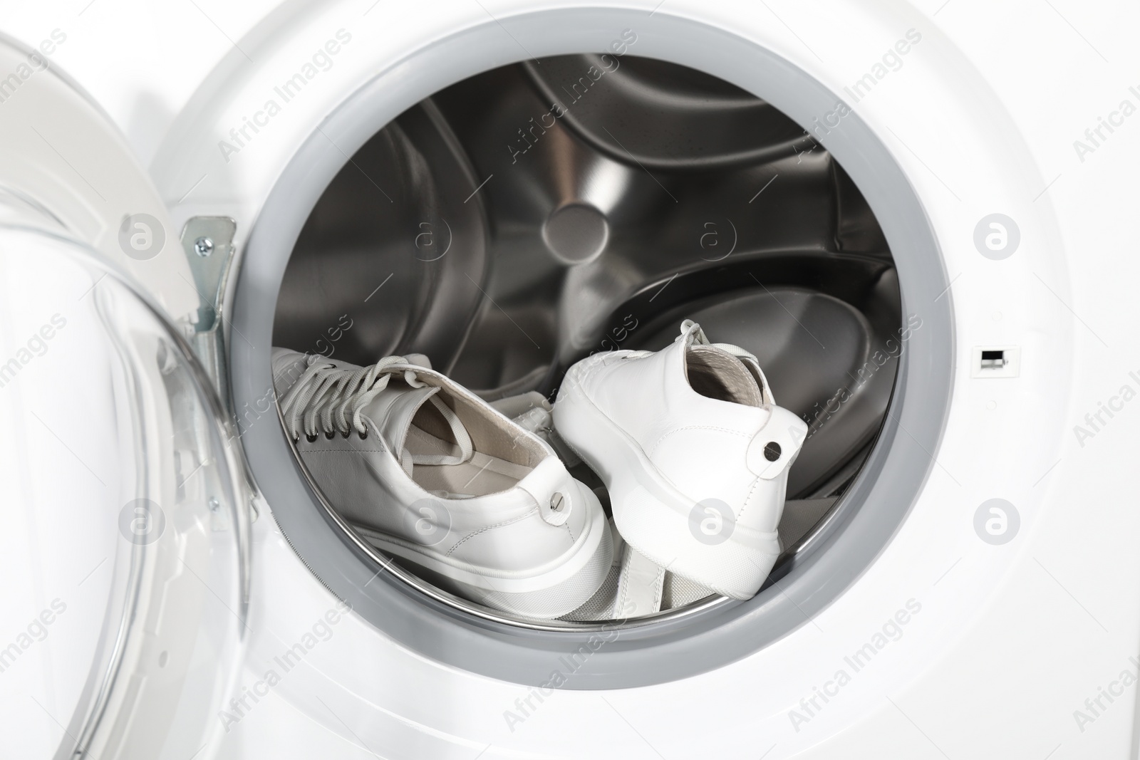 Photo of Stylish clean sneakers inside modern washing machine