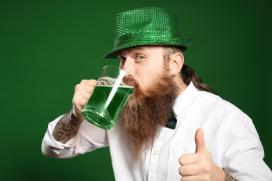 Photo of Bearded man drinking green beer on color background. St. Patrick's Day celebration