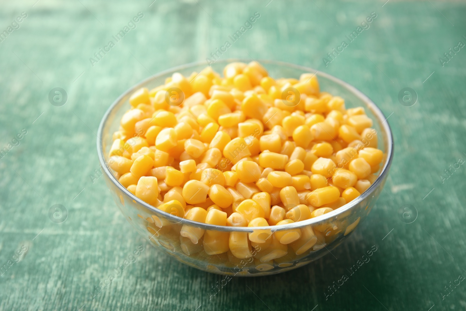 Photo of Bowl with corn kernels on green wooden background