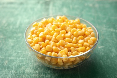 Photo of Bowl with corn kernels on green wooden background