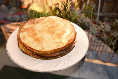 Photo of Plate of delicious crepes on black table outdoors, closeup