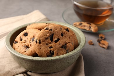 Photo of Delicious chocolate chip cookies and tea on grey table, closeup