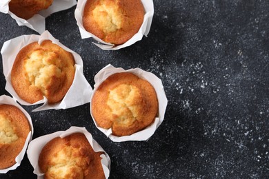 Delicious sweet muffins on black textured table, flat lay. Space for text