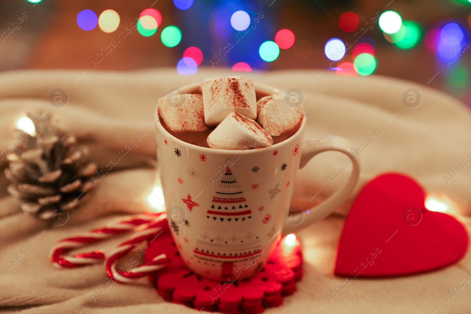 Photo of Cup of delicious hot cocoa with marshmallows and beautiful Christmas decor on white cloth, closeup