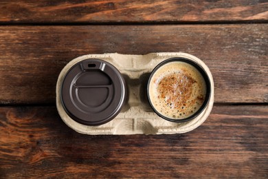 Photo of Takeaway paper cups with coffee in cardboard holder on wooden table, top view