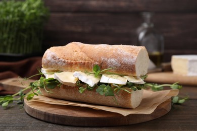 Photo of Tasty sandwich with brie cheese on wooden table