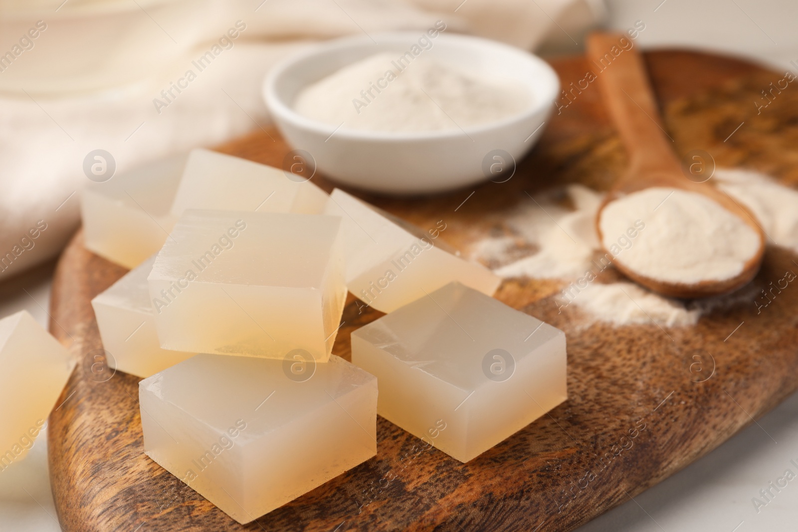 Photo of Agar-agar jelly cubes and powder on white table, closeup