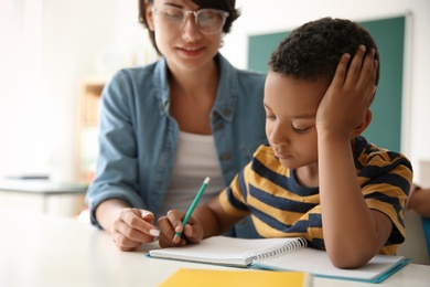 Photo of Female teacher helping child with assignment at school