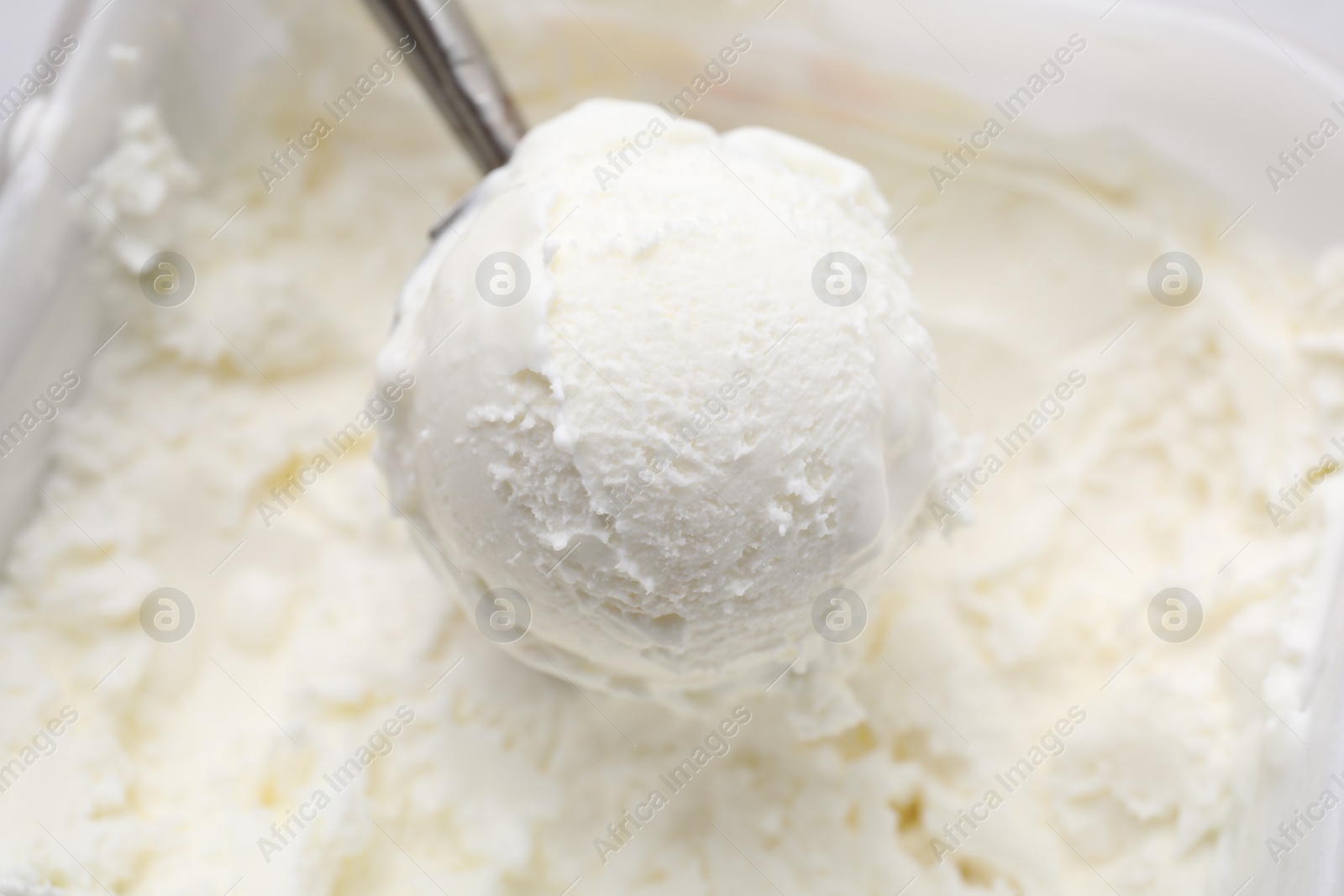 Photo of Steel scoop with tasty vanilla ice cream, closeup