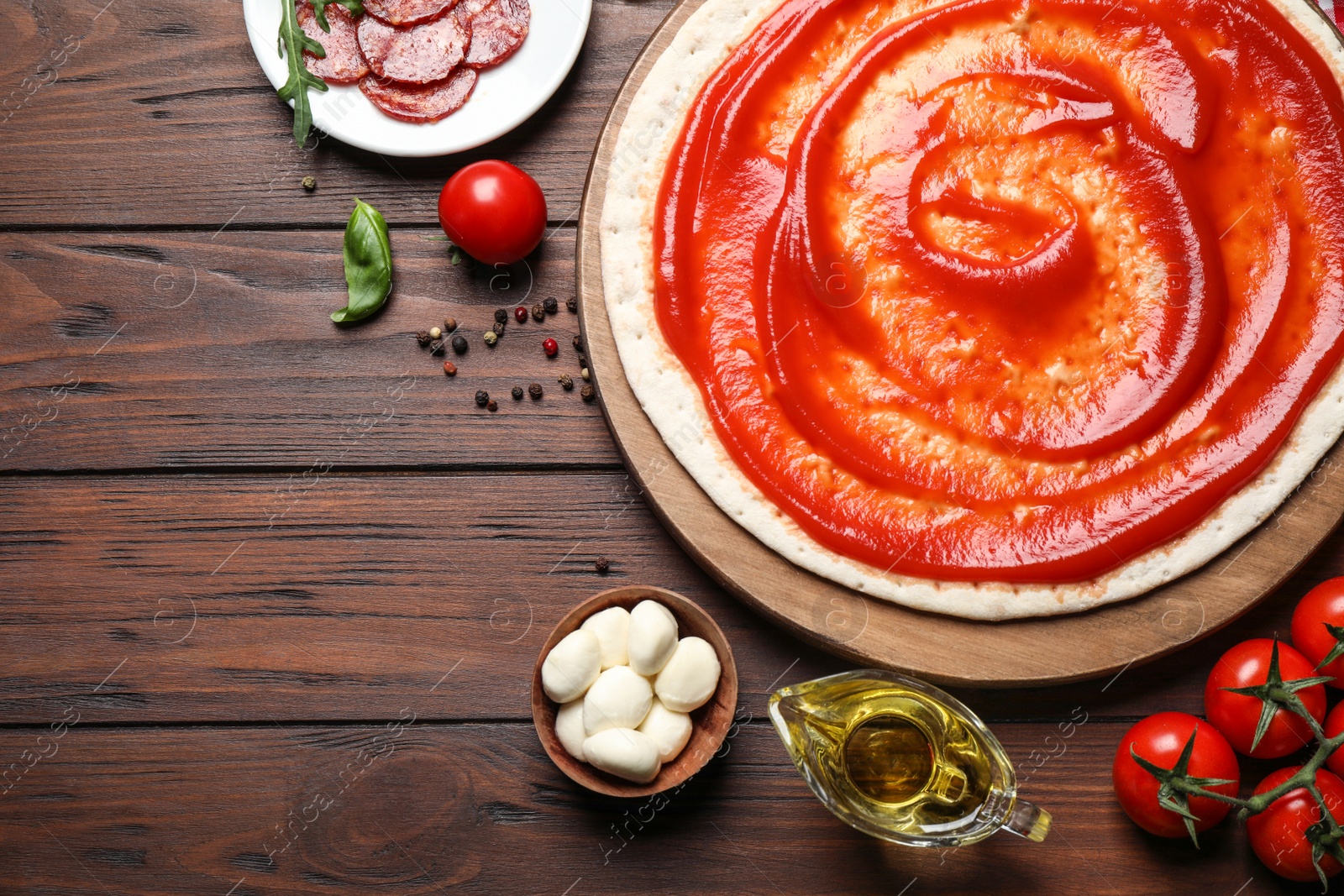 Photo of Flat lay composition with base and fresh ingredients for pepperoni pizza on wooden table