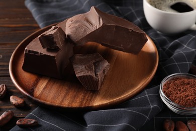 Photo of Pieces of tasty milk chocolate, cocoa beans and powder on wooden table