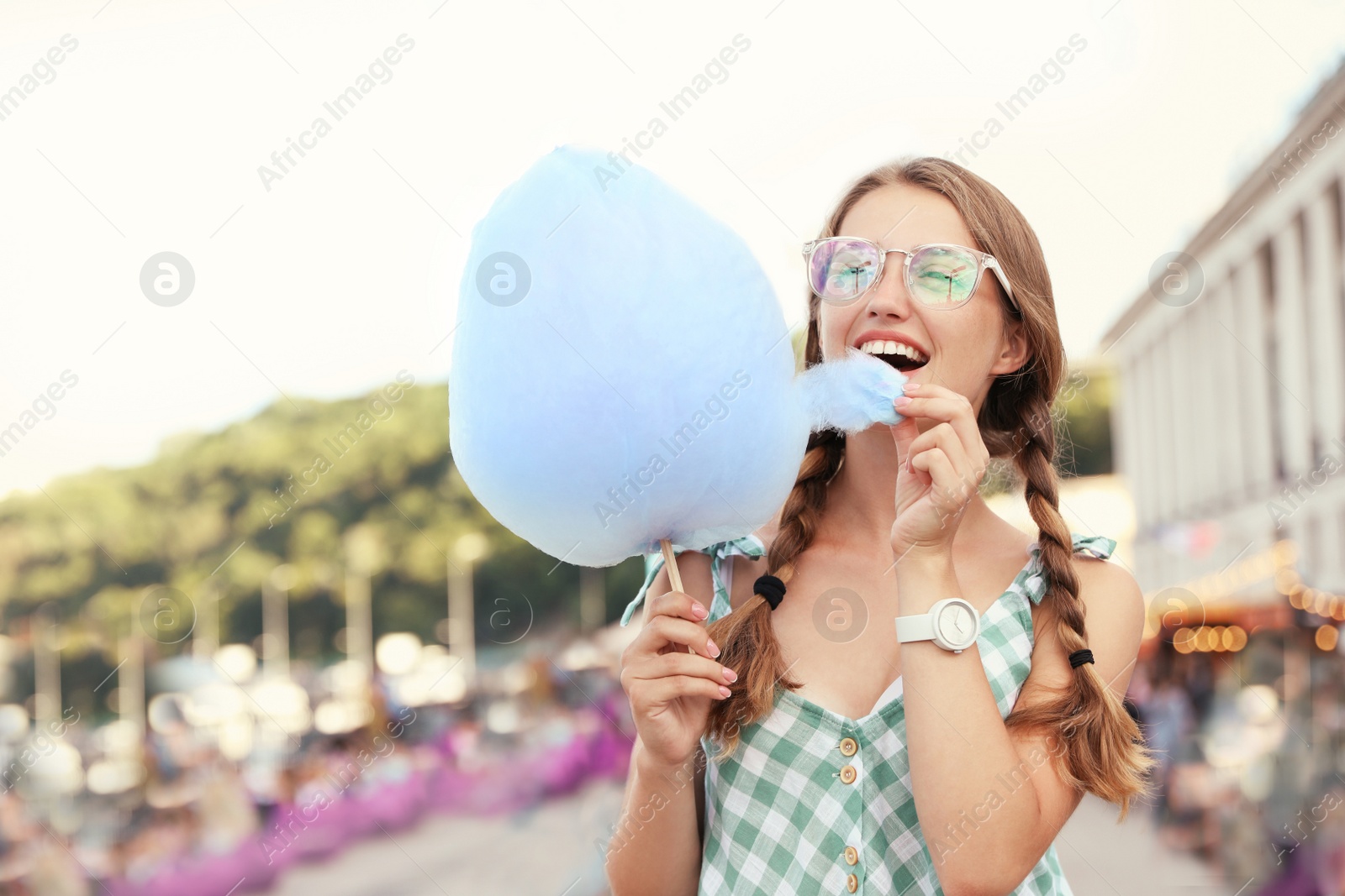 Photo of Young woman with cotton candy on city street. Space for text