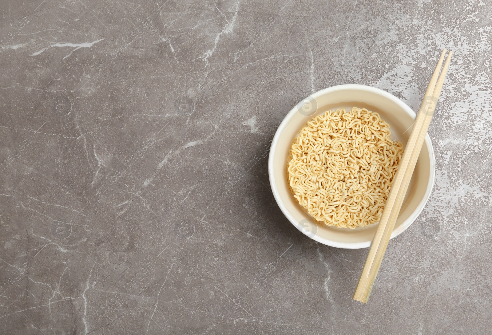 Photo of Cup of instant noodles with chopsticks on table, top view. Space for text