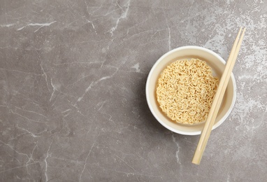 Cup of instant noodles with chopsticks on table, top view. Space for text