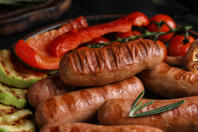Photo of Tasty fresh grilled sausages with vegetables on table, closeup