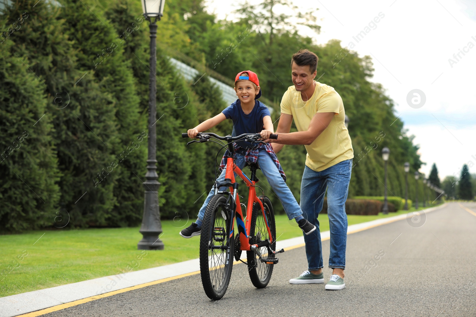 Image of Dad teaching son to ride bicycle outdoors