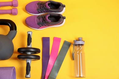Different sports equipment on yellow background, flat lay