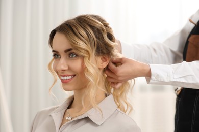 Hair styling. Professional hairdresser working with smiling client indoors, closeup