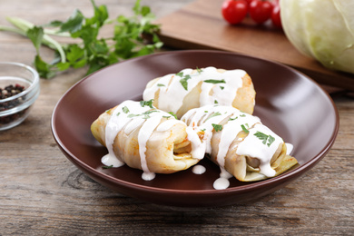 Photo of Delicious cabbage rolls served on wooden table