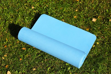 Photo of Blue karemat or fitness mat on fresh green grass outdoors, above view