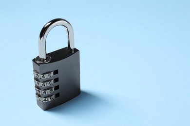 Steel combination padlock on light blue background. Space for text