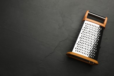 Photo of Modern grater on black table, top view. Space for text