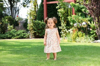 Cute little girl walking on green grass in park