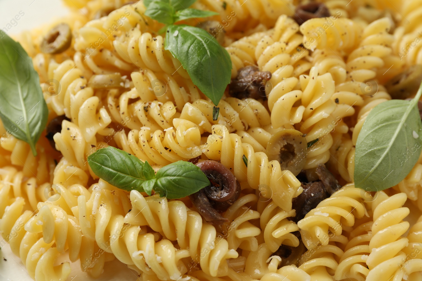 Photo of Delicious pasta with anchovies and basil as background, closeup