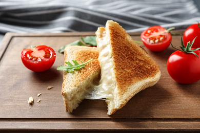 Image of Tasty toast sandwiches with cheese and tomatoes on wooden board