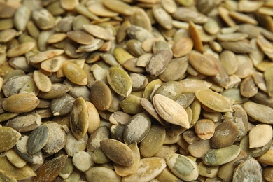 Photo of Raw peeled pumpkin seeds as background, closeup