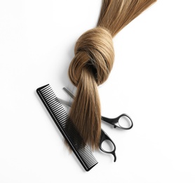 Photo of Beautiful brown hair, scissors and comb on white background, top view. Hairdresser service
