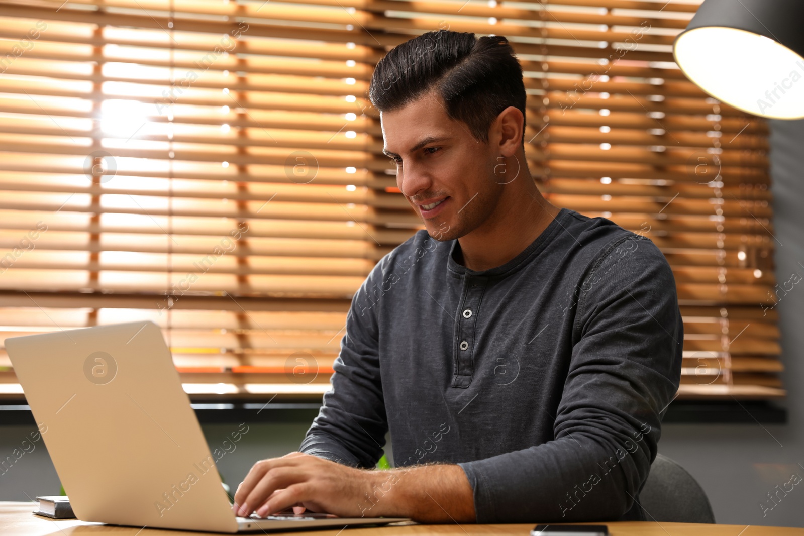 Photo of Man using laptop for search at wooden table in office