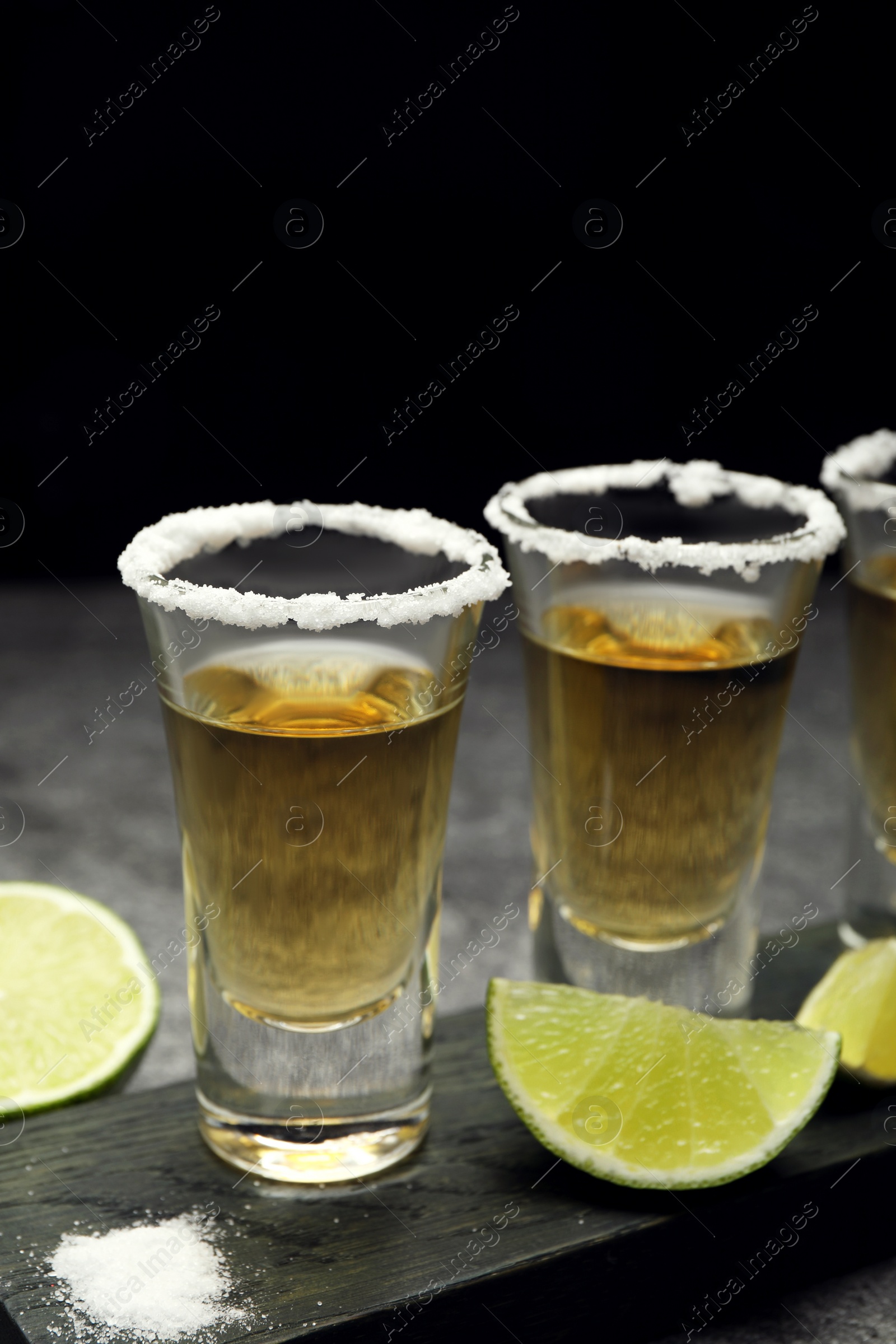 Photo of Mexican Tequila shots, lime slices and salt on grey table