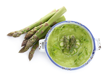 Photo of Delicious asparagus soup with arugula isolated on white, top view