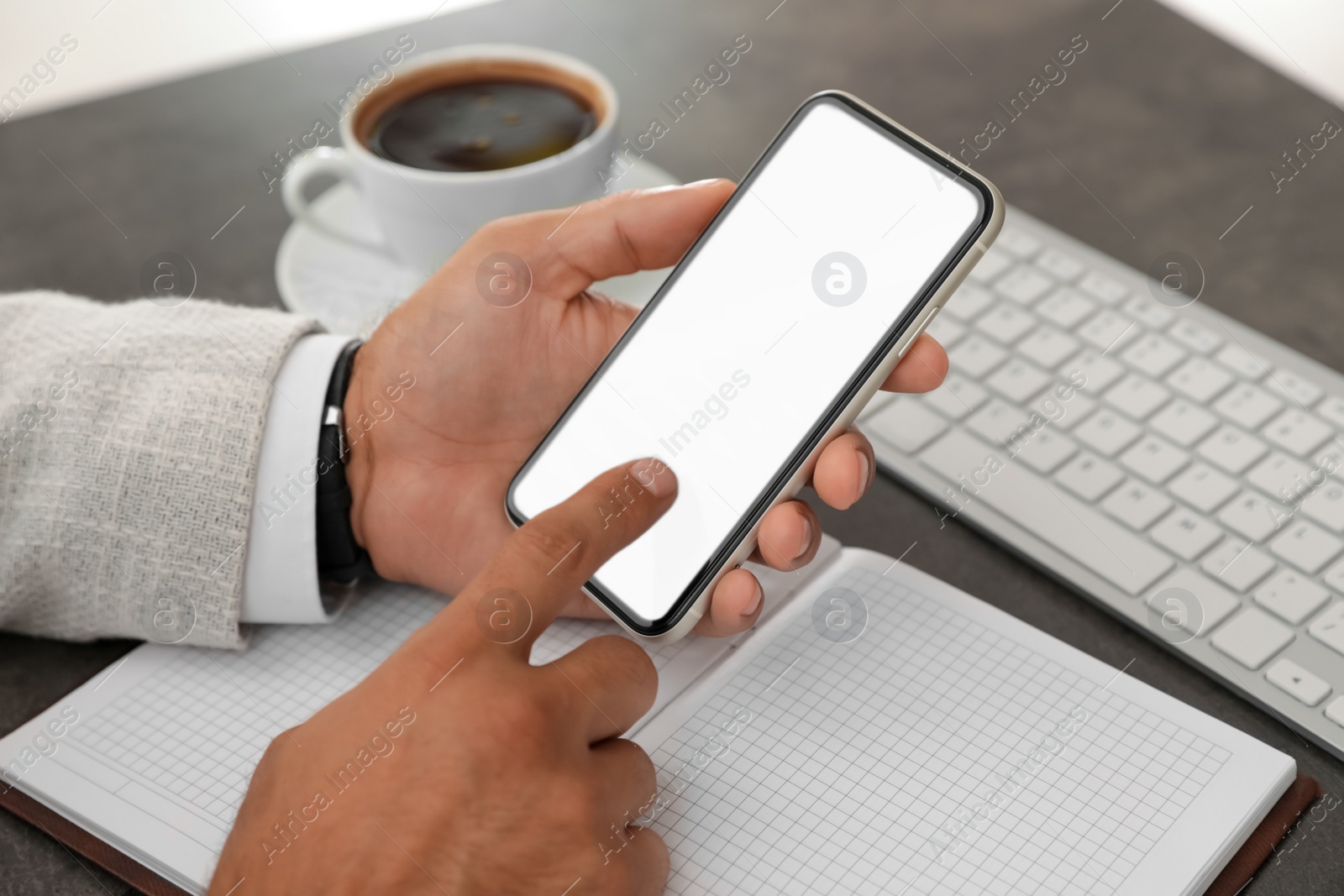 Photo of Man using mobile phone with empty screen at table, closeup