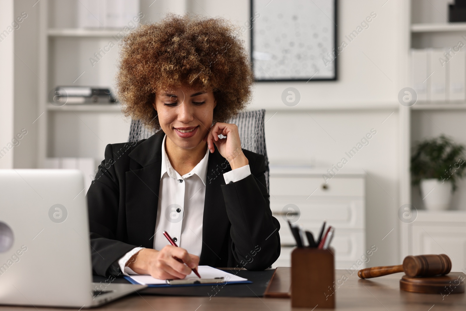 Photo of Notary with clipboard writing notes at workplace in office