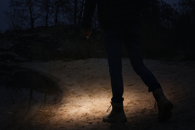 Man with flashlight walking at riverside, closeup