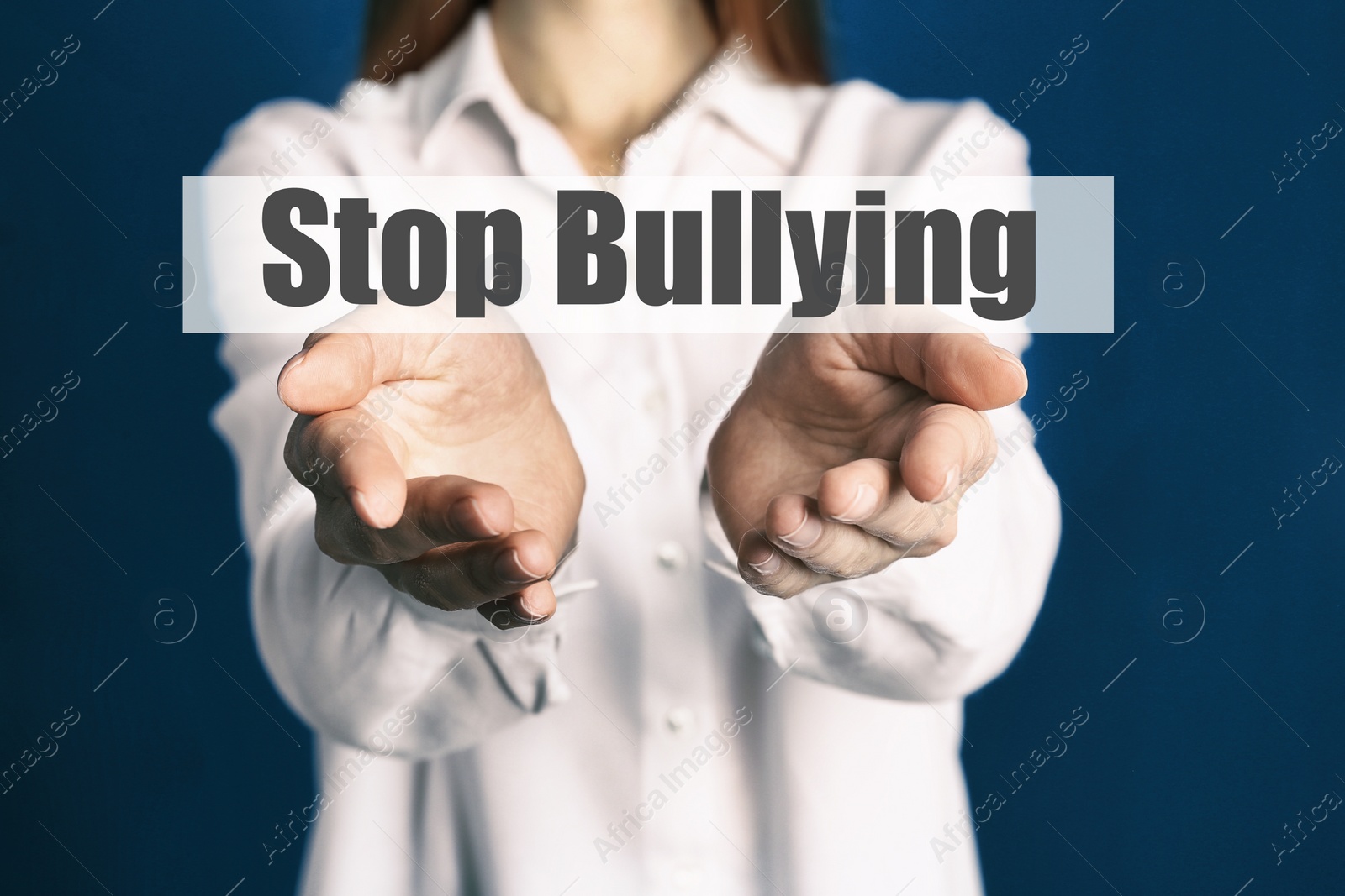 Image of Young woman showing sign STOP BULLYING on blue background, closeup 