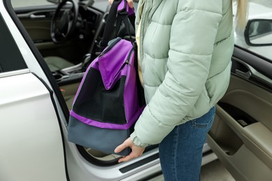 Photo of Woman putting pet carrier in car, closeup